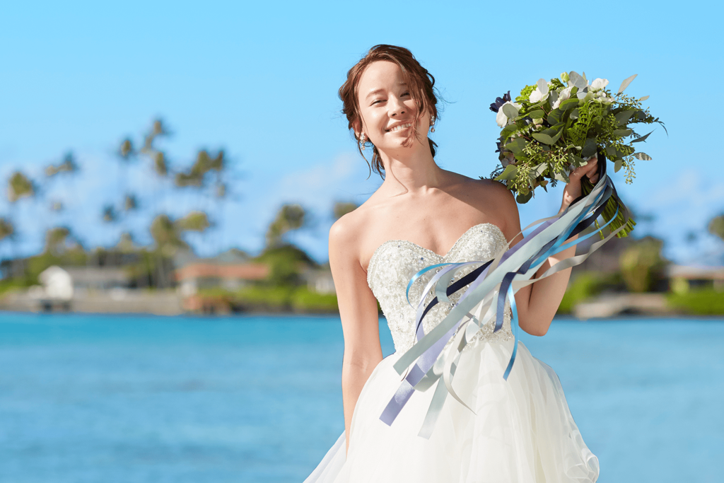 ブーケを持ち海をバックに微笑む新婦