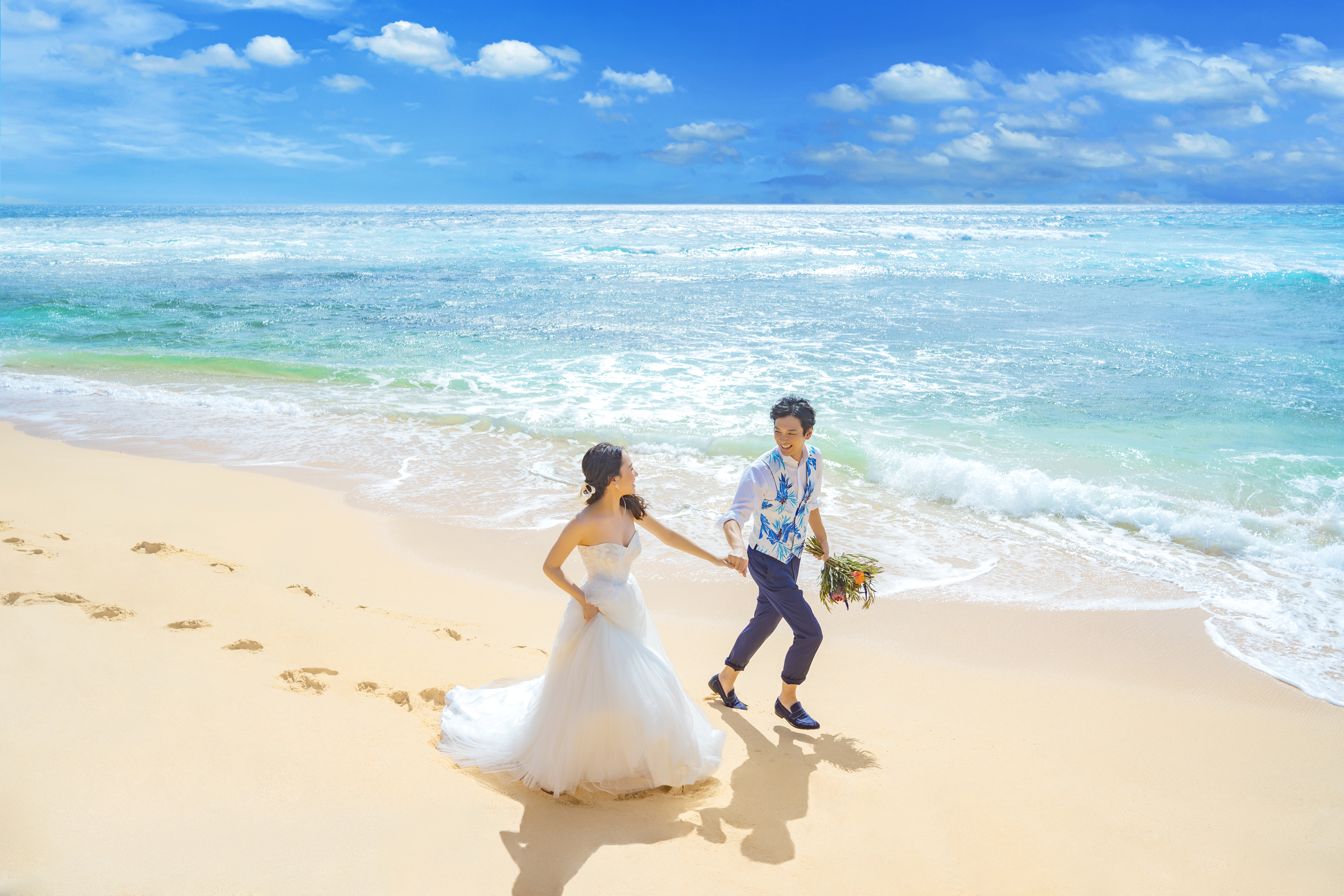 白い砂浜を走るカップル
