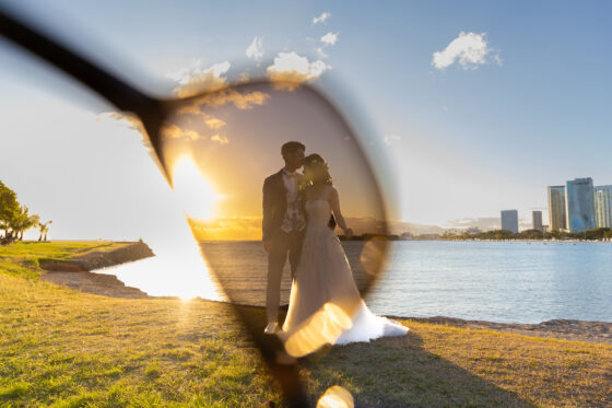 輝くサンセットとハワイの海。都会的な景色の中の新郎新婦