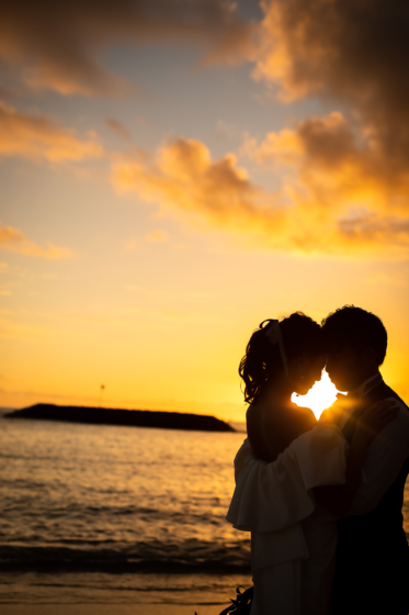 夕焼けに染まるハワイの空を背景に、新郎新婦が寄り添う姿。黄金色の光が二人の幸せを優しく包み込みます。