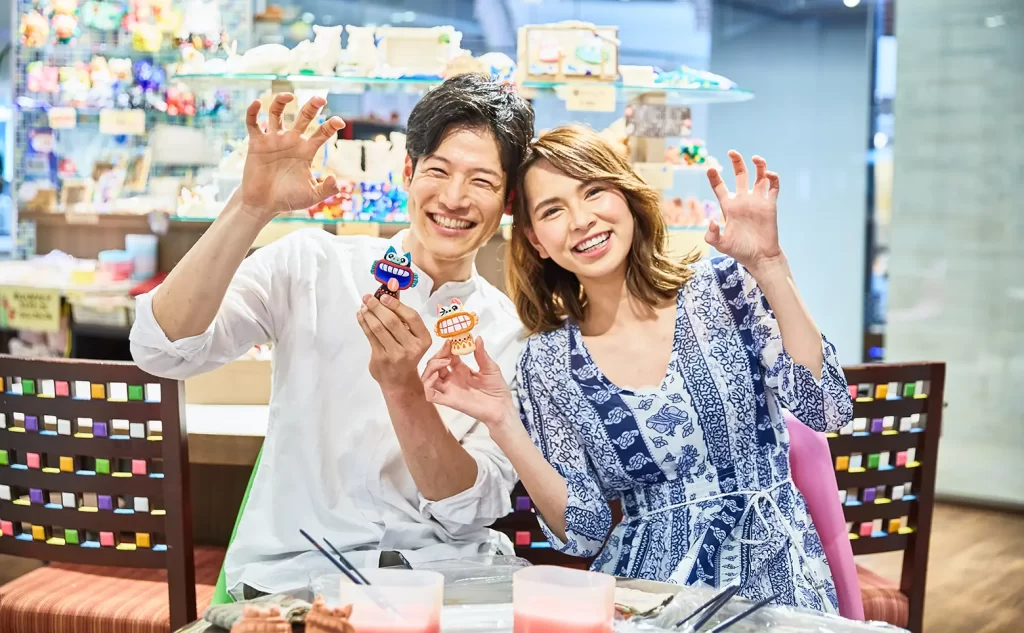 お土産を持ちポーズをとる新郎新婦