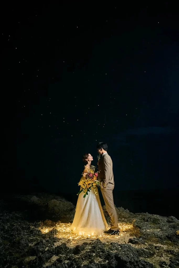 宮古島の満天の星空、ライトに照らされながら見つめ合う新郎新婦のロマンチックな夜景ショット