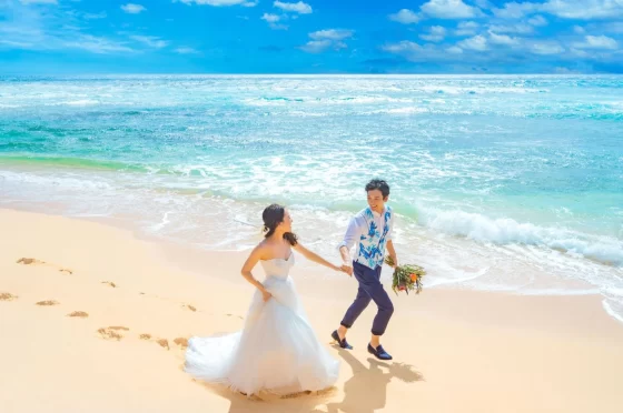 白い砂浜で手を取り合いながら駆け出す新郎新婦