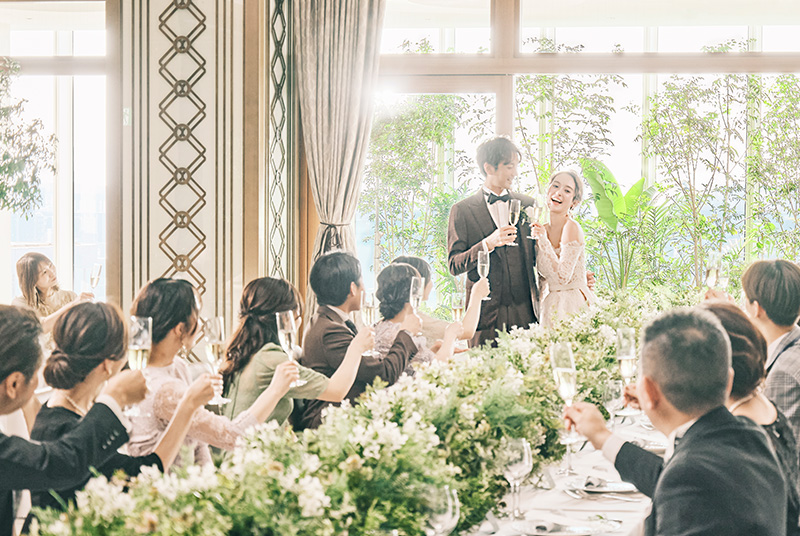 写真:青い海と空を背景に並ぶ新郎新婦