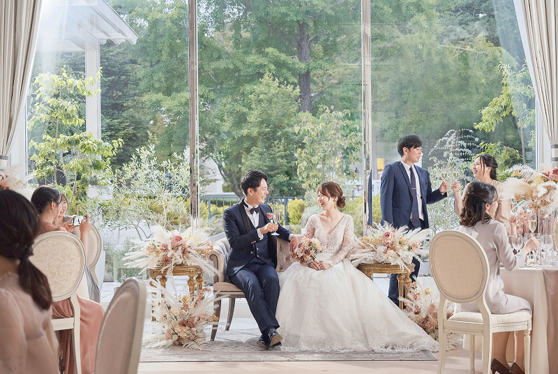 写真：青い海と空を背景に並ぶ新郎新婦