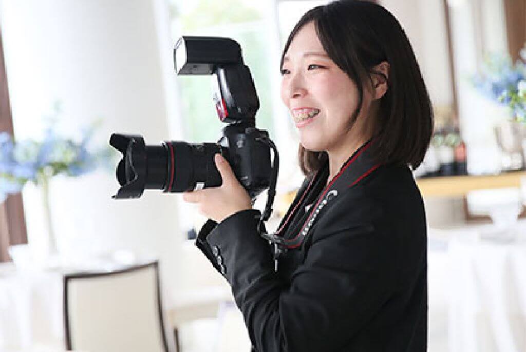 写真:笑顔で一眼レフカメラを構える丸山