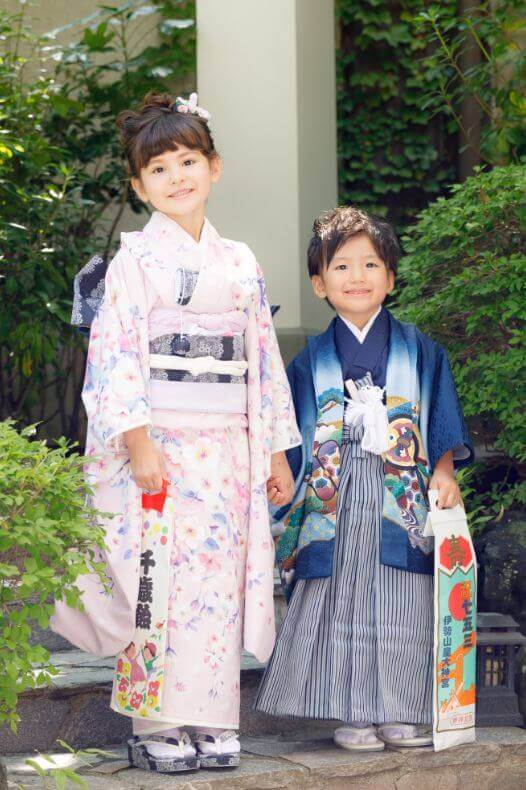 薄ピンクの振り袖を着た7歳の女の子と袴姿の5歳の男の子が手をつないで微笑んでいる写真