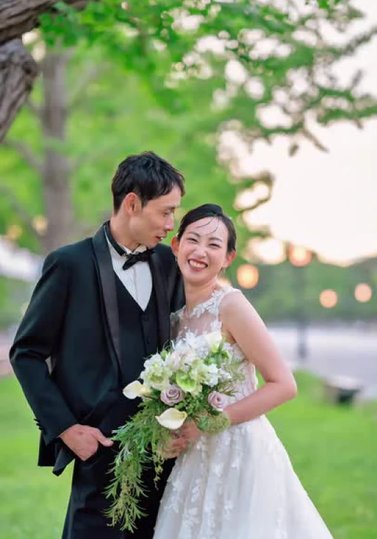 緑に囲まれて笑顔を交わす新郎新婦